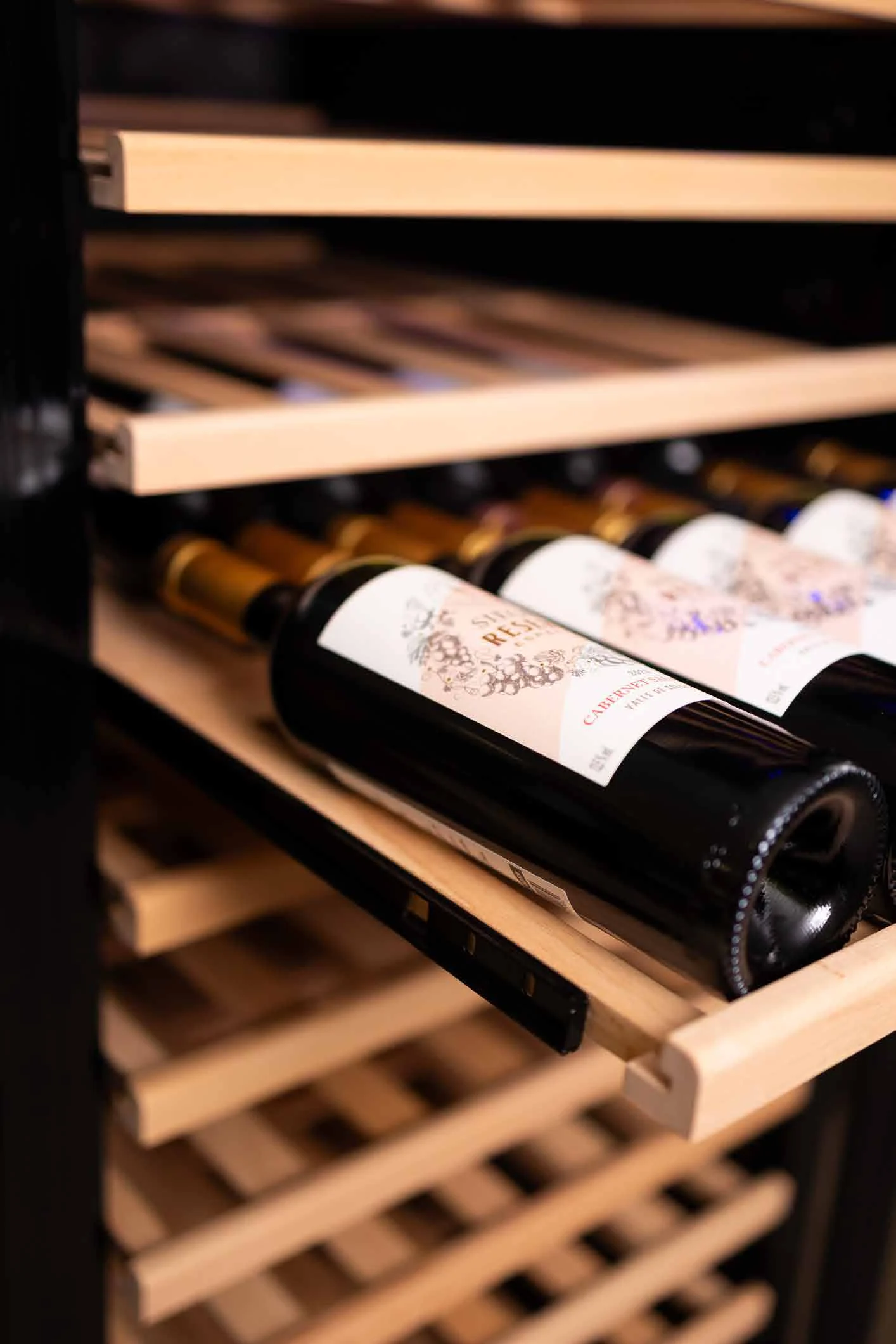 Garrafa de vinho deitada em prateleira de madeira naval da adega Benmax BAC209