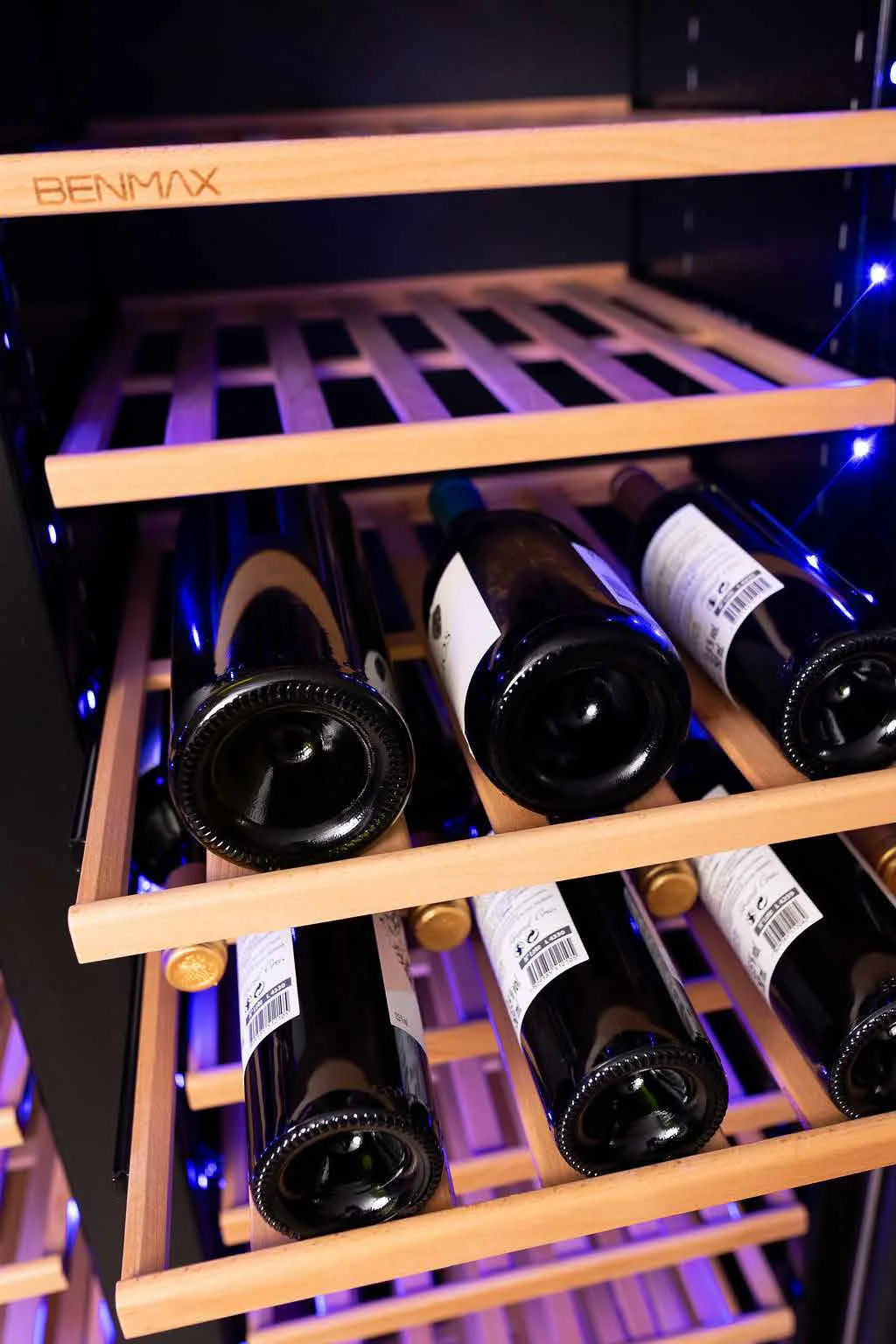 Garrafas de vinho de diferentes tamanhos acomodadas nas prateleiras da adega Benmax BAC218BA