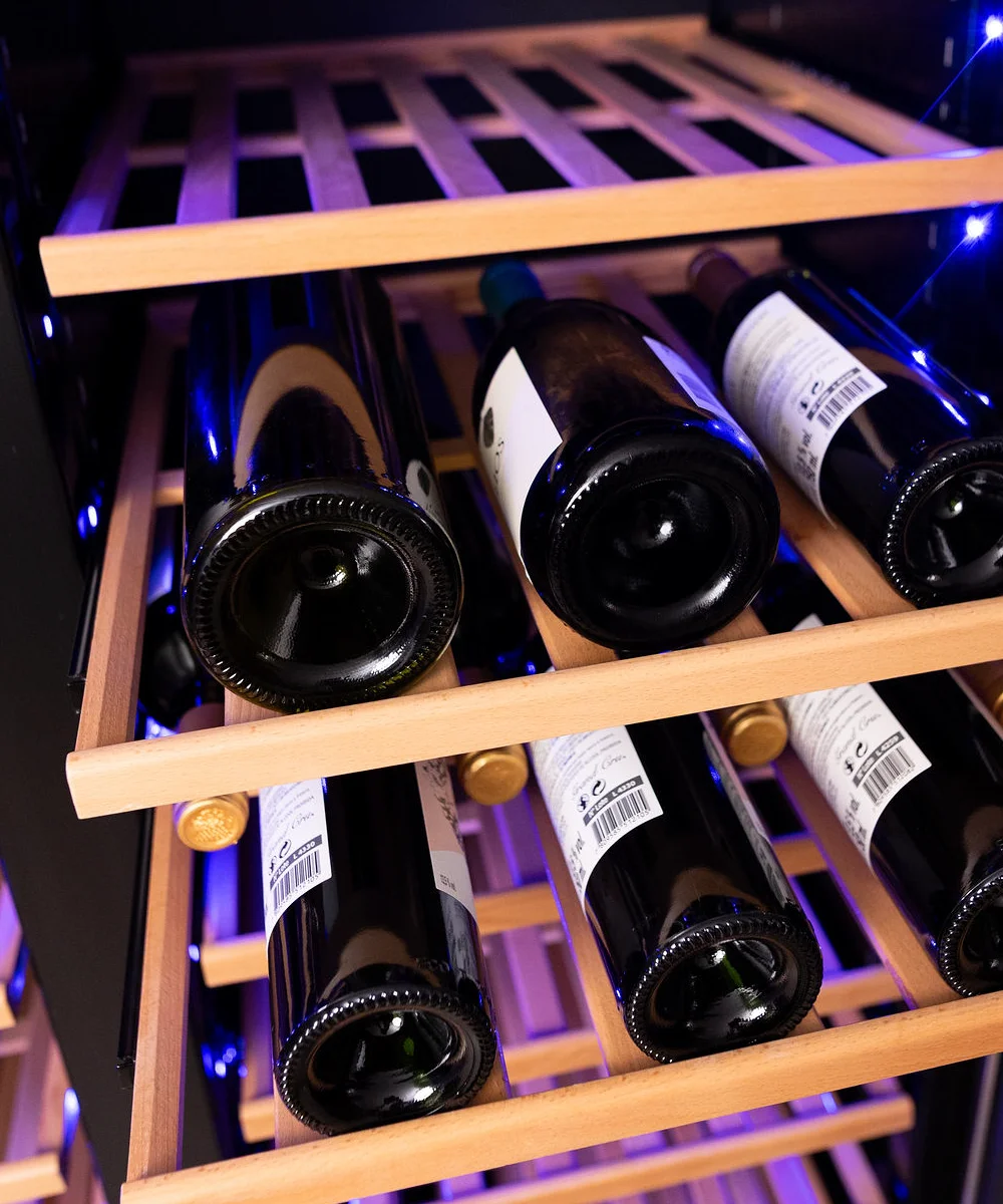 Garrafas de vinho de diferentes tamanhos acomodadas nas prateleiras da adega Benmax